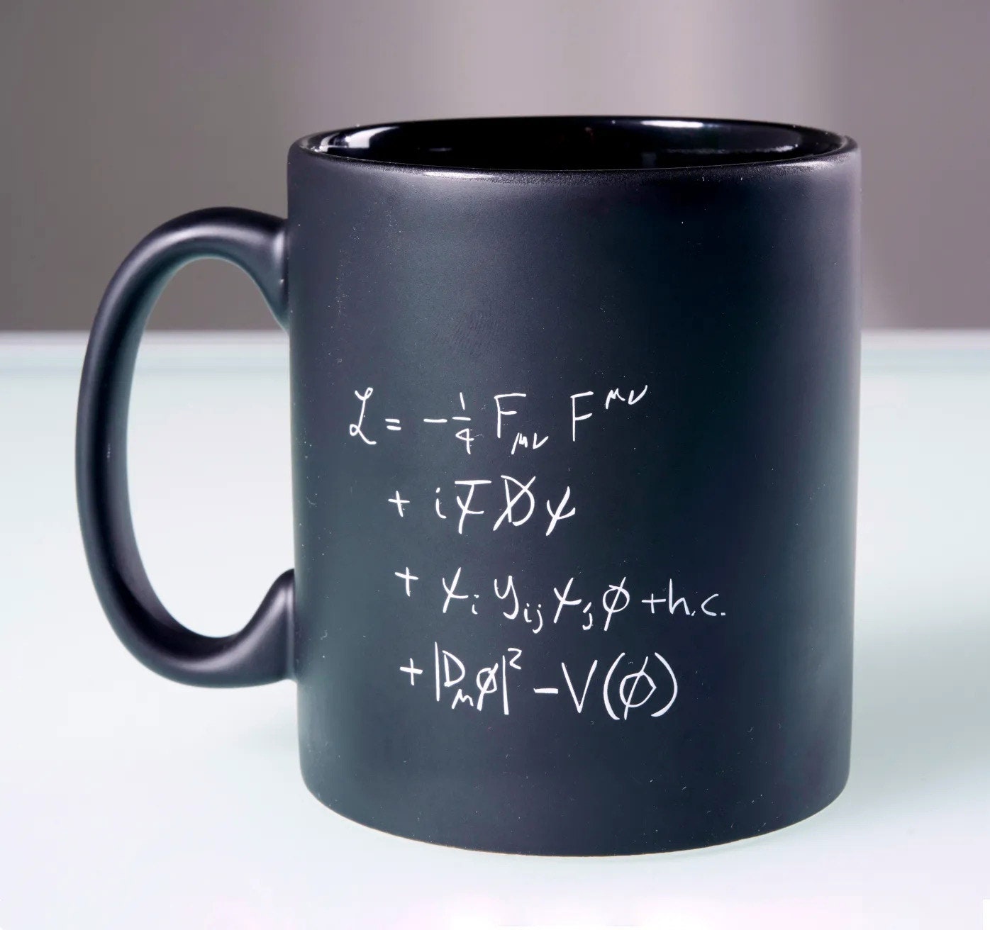 Une tasse noire avec une formule scientifique imprimée en lettres blanches