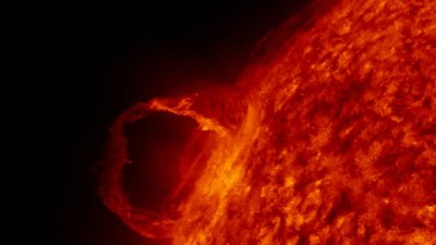 La surface du soleil avec un filament de plasma tacheté d'orange, avec le noir de l'espace derrière.