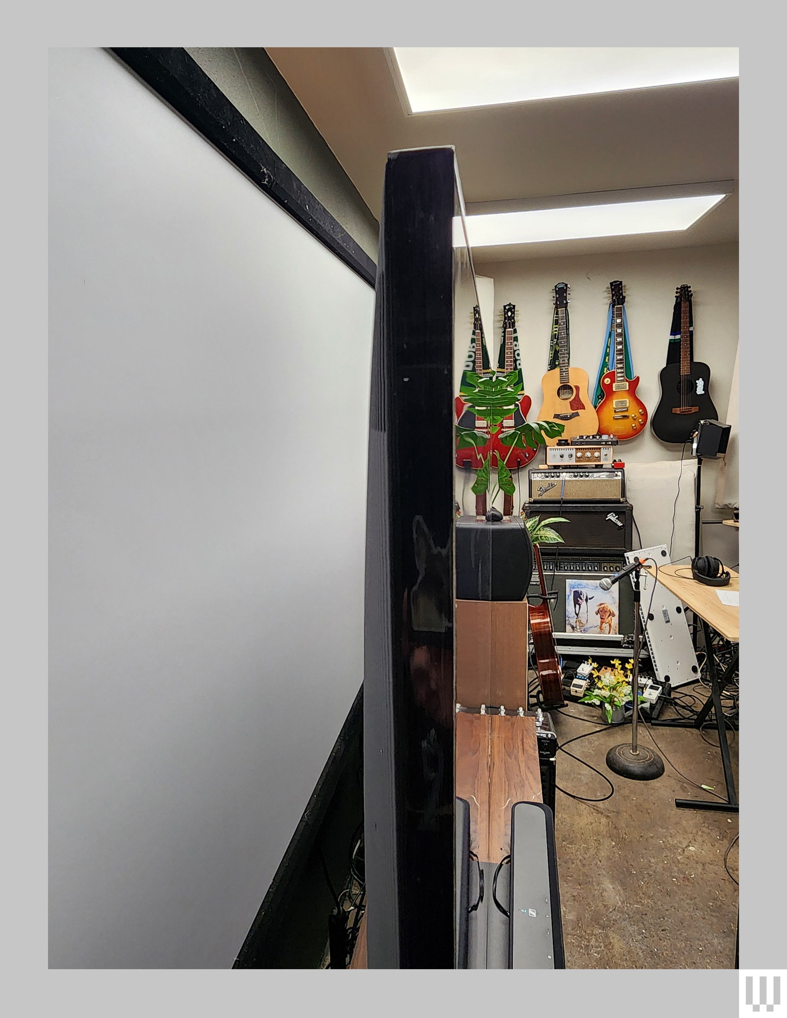 Vue latérale d'un téléviseur noir mince avec des guitares accrochées au mur en arrière-plan